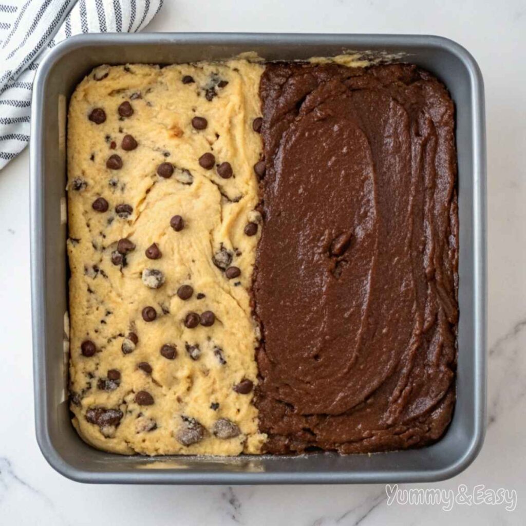 Brookie layers with brownie batter and cookie dough in a baking pan.